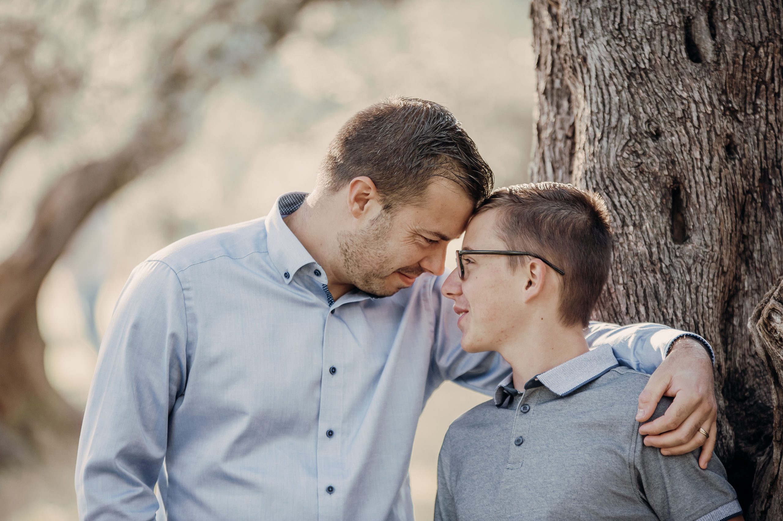 Un père et son fils front contre front près d'un arbre